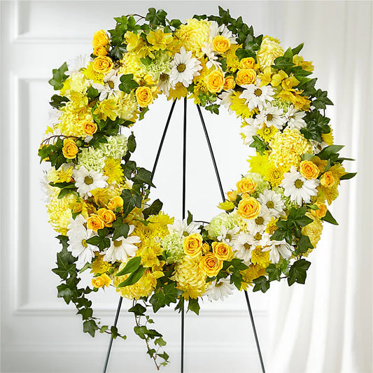 The Golden Hour Sympathy Wreath is a radiant funeral wreath designed to bring warmth, comfort, and remembrance during times of loss. Featuring a beautiful combination of white chrysanthemums, green and yellow carnations, yellow spray roses, large spider mums, and lush greenery, this large floral wreath symbolizes peace, renewal, and eternal light.

Features:
White chrysanthemums for purity and remembrance
Green and yellow carnations symbolizing renewal and love